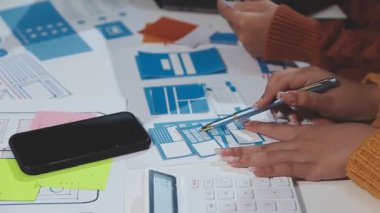 Bilgisayarlı ve akıllı telefonlu genç bir kadın ofiste çalışıyor..