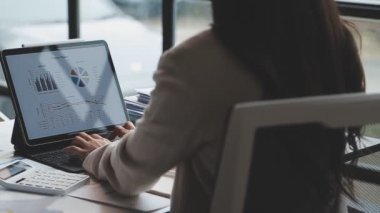 Ofis masasında dizüstü bilgisayarda çalışan genç bir iş kadını..