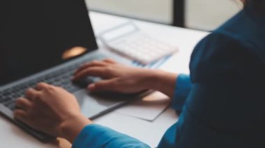 Ofiste laptop üzerinde çalışan genç iş kadını.