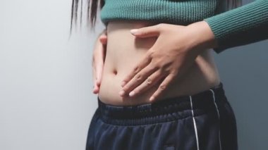 Genç bir kadın koca göbeğini gösteriyor.