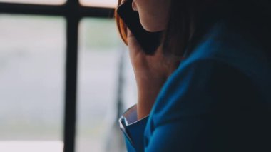 Kafede otururken cep telefonu kullanan genç bir kadın.