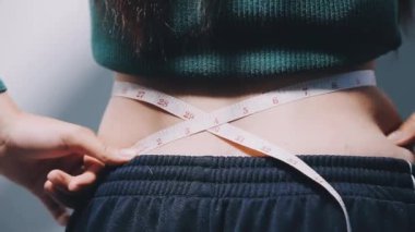 Kadın ölçü bandıyla belini ölçüyor.