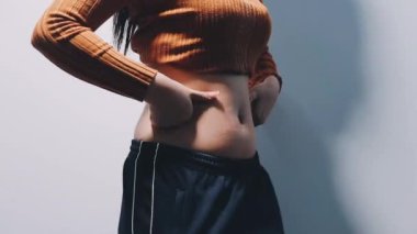 Beyaz tişörtlü kadın. Gri arka planda karın ağrısı var.