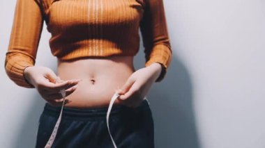 Genç bir karnının belini ölçen bir kadın.