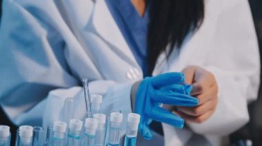 Laboratuvarda mavi sıvıyla beyaz önlüklü bilim adamının yakın çekimi.