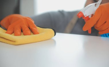 Evde bez ve dağıtıcı kullanan kadın masasını temizliyor.