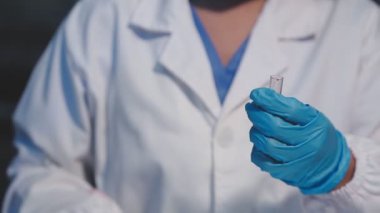 Laboratuvarda elinde kan örneği olan cam tüp tutan bir bilim adamı..