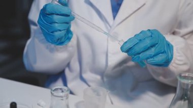 Laboratuvar bilim adamı elinde sıvı olan tüpü tutuyor, kapat. Laboratuvarda kimyasal deney..