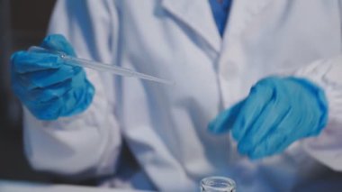 Laboratuvar asistanı bardağı sıvıyla tutuyor, yakın plan.