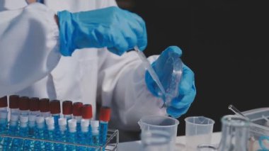 Yakın plan - mikroskop ile koruyucu maskeli bir laboratuvar çalışanı.