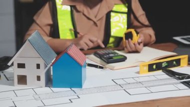 Mavi kasklı genç bayan mimar planlı ve hesap makineli.