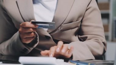 Kredi kartı olan genç bir kadın cep telefonunu ev ödemesi için kullanıyor.