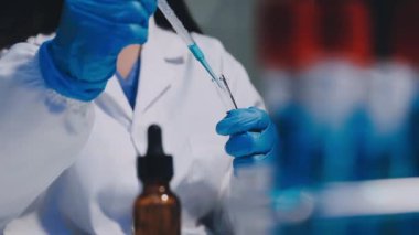 Koruyucu üniformalı bilim adamı elinde aşı şişesi tutuyor.