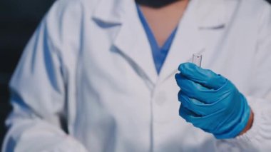 Bilim adamı elinde sıvı olan bir tüp tutuyor.