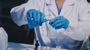 Laboratuvardaki bilim adamı elinde sıvı olan test tüpünü tutuyor.