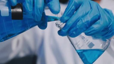 Üzerinde test tüpü olan mavi ceketli laboratuvar asistanı.