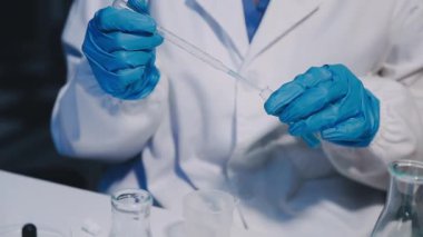 Yakın çekim - Bilim adamlarının elleri test tüpünü tutuyor ve kameraya bakıyor.