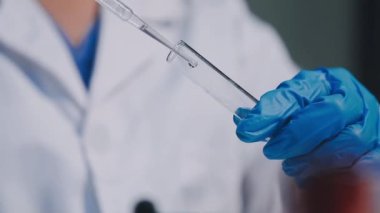 Yakın plan - Doktorun elinde bir tüp sıvı ile test tüpü tutması..