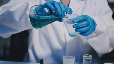 Laboratuvardaki bilim adamı. Laboratuvarda bir bardak su tutan bilim adamının ellerini kapatın..