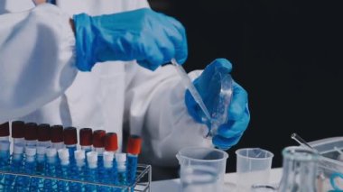 Test tüpü tutan koruyucu eldivenli laboratuar asistanı..