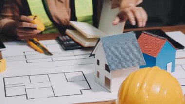 Ev modeli ve mimarı olan kadın elleri masanın üstünde, yakın plan..