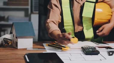 Ofis masasında planları olan genç bir mimar.