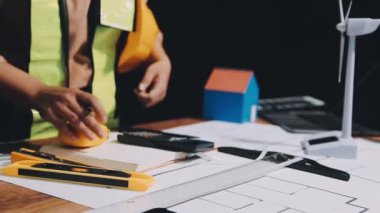 Genç Asyalı mimar kadın ofiste mimari planla çalışıyor.