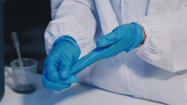 Yakın plan - kadın doktor mavi lastik eldiven tutuyor ve eldiven takıyor