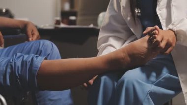 Doktor bir hastanın ayağını muayene ediyor.
