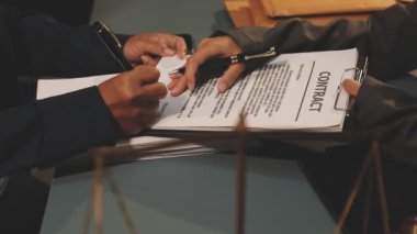 Adam kalem yazıyor ve masaya belgeler imzalıyor.