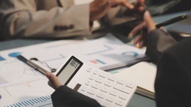 Yatırım grafiklerini hesap makinesi ve dizüstü bilgisayarla analiz eden iş adamı