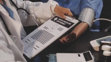 Beyaz önlüklü doktor elinde şırınga ve kan basıncı tutuyor.