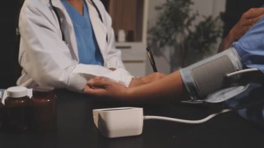 Doktor, hastanede steteskoplu hastanın kan basıncını ölçüyor.