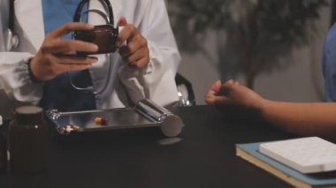 Doktor eli steteskop ve haplarla beyaz bir masada.