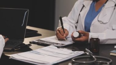 Kadın doktor, ofiste hasta için reçete yazıyor.