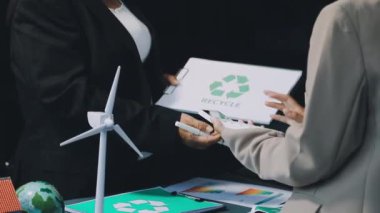 Takım elbiseli ve takım elbiseli iş adamı elinde yeşil bitkilerle kağıt model tutuyor. sürdürülebilir geliştirme kavramı