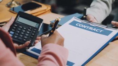 Ofisteki mali belgeleri hesaplamak için hesap makinesi kullanan iş adamı.