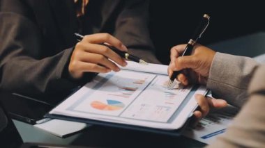 İş adamlarının elleri toplantı odasındaki mali raporun grafiğine işaret ediyor..