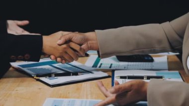 İş adamı ve kadın ofiste bir belgeyle el sıkışıyor