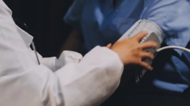 Hastanede tansiyonunu ölçen doktorun elini kapatın.