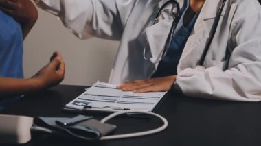 Doktorlar steteskop ve kalemle el ele tutuşuyorlar.