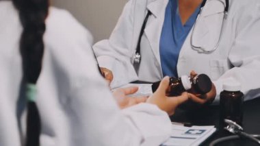 Kadın doktor reçete yazarken elinde kalem tutuyor.