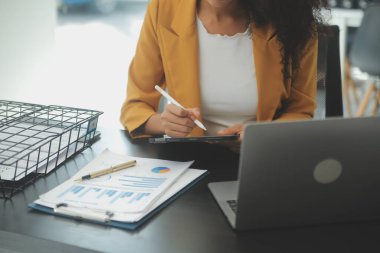 Hesap makinesi ve dizüstü bilgisayarı kullanarak ahşap masa, vergi, muhasebe, istatistik ve analitik araştırma konseptine matematik finansmanı sağlayan İş kadını kapat