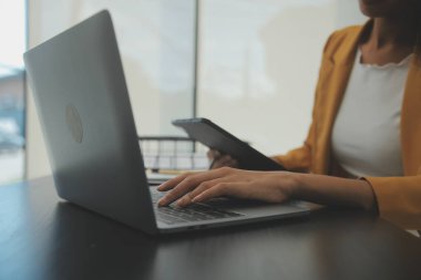 Hesap makinesi ve dizüstü bilgisayarı kullanarak ahşap masa, vergi, muhasebe, istatistik ve analitik araştırma konseptine matematik finansmanı sağlayan İş kadını kapat