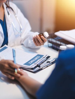 Ofiste çalışan ve hastayı dinleyen doktor semptomlarını, sağlık hizmetlerini ve yardım kavramlarını açıklıyor.