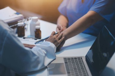 Doktor umut veriyor. Genç kadın hekimin avuçlarında elini tutan yaşlı bayanın gülümsemesini yakından çek. Beyaz önlüklü kadın bakıcı yaşlı insanı cesaretlendiriyor.