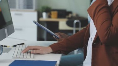 İş yerinde dizüstü bilgisayar ve tablet bilgisayar kullanan genç kadın tasarımcı
