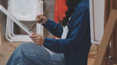 Beyaz stüdyodaki genç Asyalı kadın sanatçı.