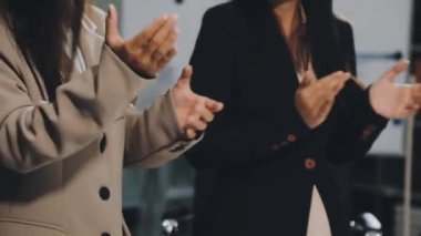Resmi olarak genç bayan meslektaşlar modern ofis içinde elleri ile ayakta dururlar.