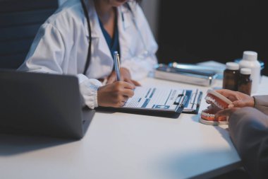 Diş sağlığı kliniğinde planlı diş tedavisi hakkında dişçi ve hasta tartışması, doktorlar konuşur ve çalışır. Sağlık Bakanlığı Tıp Konferansı Konsepti